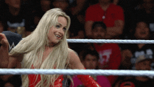 a woman in a red outfit is standing in a wrestling ring smiling