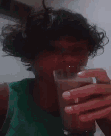 a person with curly hair is drinking from a plastic cup