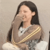 a young woman is covering her nose with her hand while laughing .