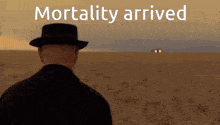 a man in a hat stands in a field with the words " mortality arrived " written above him