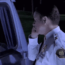 a police officer talking on a cell phone in front of a police van