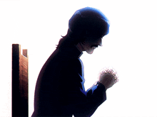 a man with his hands folded praying in front of a white wall