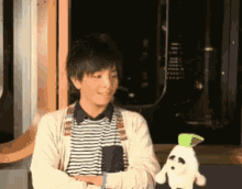 a young man holding a stuffed animal with a green head