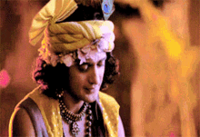 a man wearing a turban with flowers on it and a peacock feather on his head .