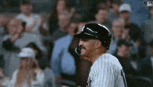 a baseball player with a mustache wearing a helmet stands in front of a crowd of people .