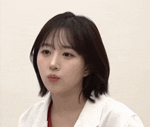 a woman wearing a white coat looks at the camera