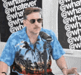 a man wearing sunglasses and a blue shirt is speaking into a microphone .