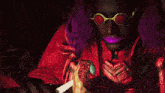 a man with purple hair and red glasses is eating a steak
