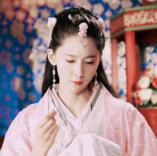 a woman wearing a pink and white kimono with a flower in her hair