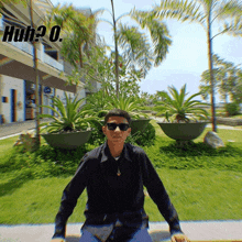 a man wearing sunglasses is sitting in front of a sign that says huh? o.