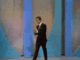 a man in a suit and tie is standing on a blue stage .