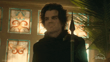 a man holding a spear in front of a stained glass window with disney + written on it