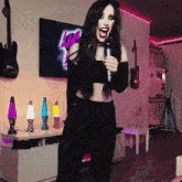 a woman singing into a microphone in front of a tv that says love on it