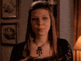 a woman wearing a black lace top and a black necklace is looking at the camera