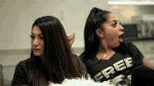 two women are sitting next to each other and one of them is wearing a free shirt