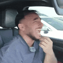 a man with a beard is sitting in a car laughing