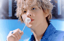 a young man blowing a dandelion with a blue background