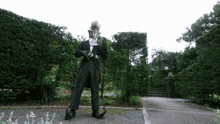 a man in a tuxedo is standing in a park