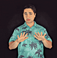 a man in a blue shirt with palm trees on it is making a funny face