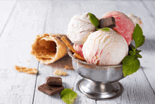three scoops of ice cream in a silver bowl on a table