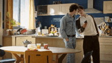 two men standing in a kitchen with a sign on the wall that says " simple is the key "