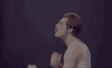 a man in a white tank top is standing on a stage with his fist in the air .