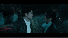 a man and a woman are looking at each other in a dark room in a movie .