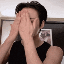 a woman covering her face with her hands in front of a picture frame