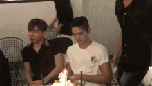 a man sitting at a table with a birthday cake and candles