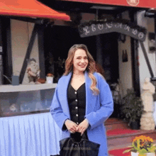a woman in a blue coat is standing in front of a building that says leonardo on it