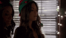 two women wearing elf hats are standing next to each other in front of a window