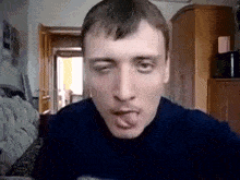 a man is sticking his tongue out while sitting on a couch .