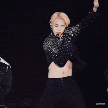 a man with a tattoo on his stomach is dancing on a stage with otherher written on the bottom right