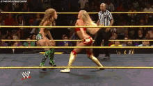 two women are wrestling in a wrestling ring with a referee in the background and the letters w on the ring