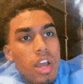 a close up of a man 's face with a blue shirt on