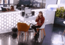 a woman sits in a chair in front of a computer in an office