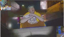 a man in a yellow shirt is sitting on a roller coaster at night .
