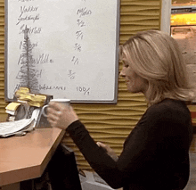 a woman is holding a cup of coffee in front of a white board that says yakker on it
