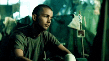 a man with a shaved head is sitting in front of a sign that says f