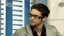 a man wearing glasses and a striped shirt looks at the camera .
