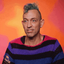 a man with a mohawk and a striped sweater looks at the camera