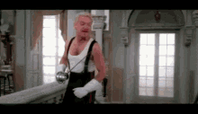 a man in overalls and white gloves is holding a sword .