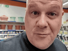 a close up of a man 's face in a store with a green exit sign in the background