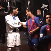 two soccer players shaking hands with one wearing a jersey that says emirates