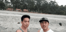 two young men standing on a beach one wearing a hat that says ' abercrombie & fitch ' on it