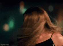 a woman 's hair is blowing in the wind and she is wearing a black dress .