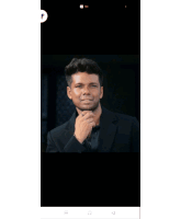 a man in a black suit adjusts his tie