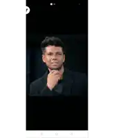 a man in a black suit adjusts his tie