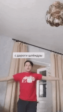 a man in a red shirt is standing in a room with his arms outstretched ..