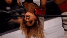 a blonde woman is upside down in a wrestling ring
